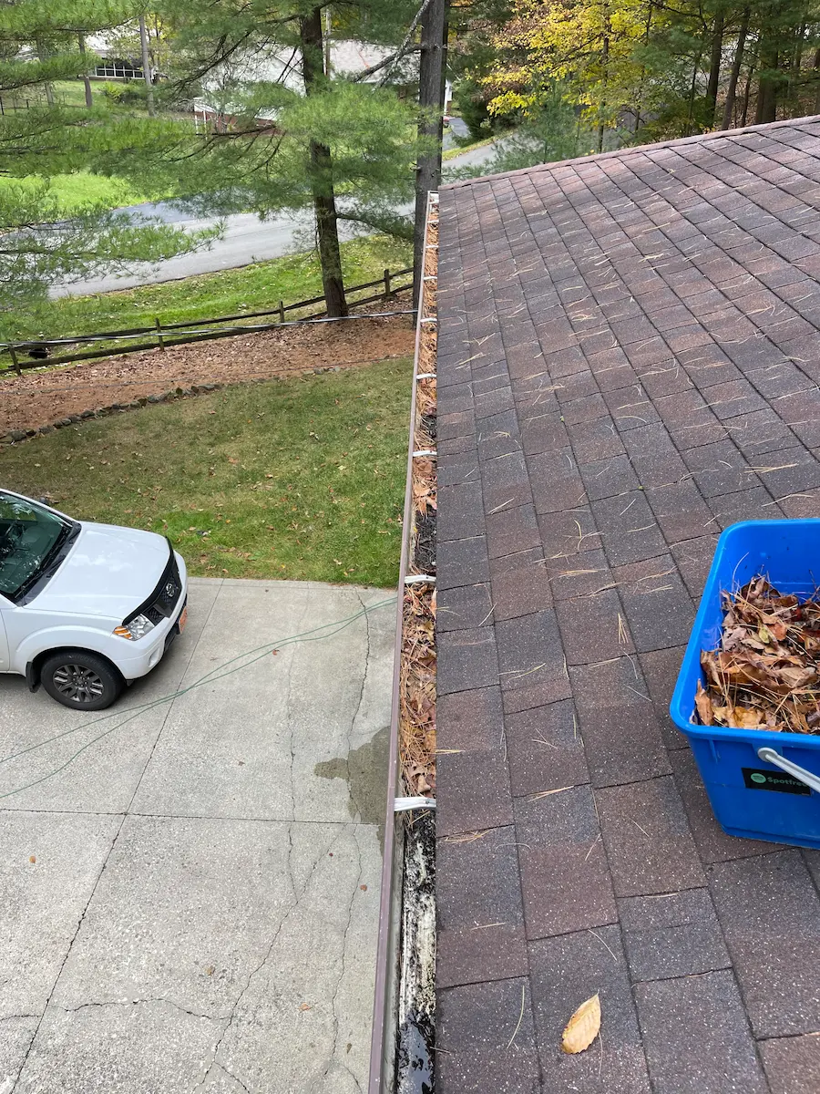 Process of Gutter Cleaning Leaves and debris being collected in a bucket by power clean technician