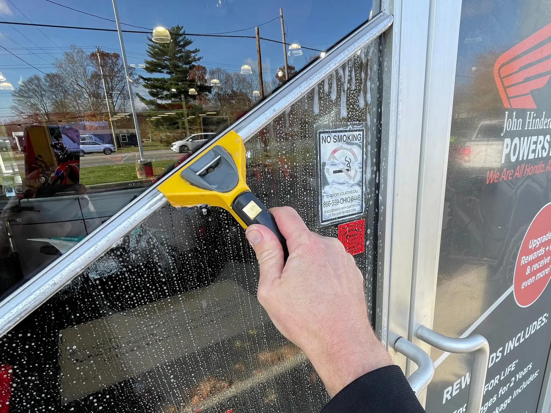 Window Cleaning at John Hinderer Close up of a power clean technician squeeging a window at John Hinderer Honda Power Store in Heath, OH