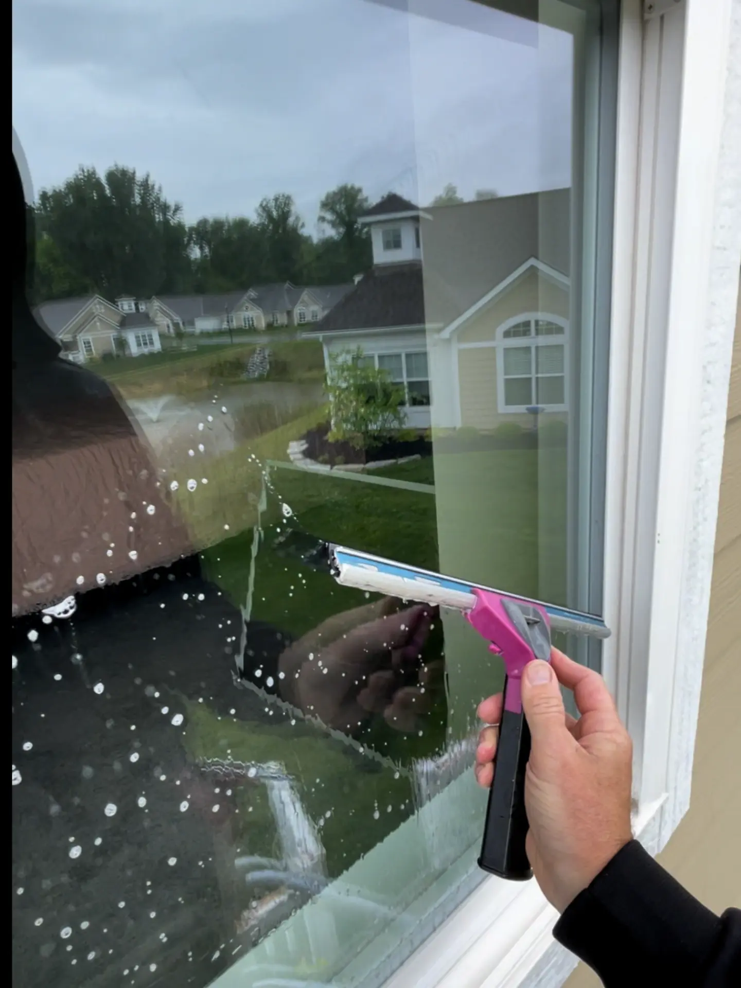 Up close of Power Clean cleaning a window with a squeegee with a reflection of Buckeye Lake in the background