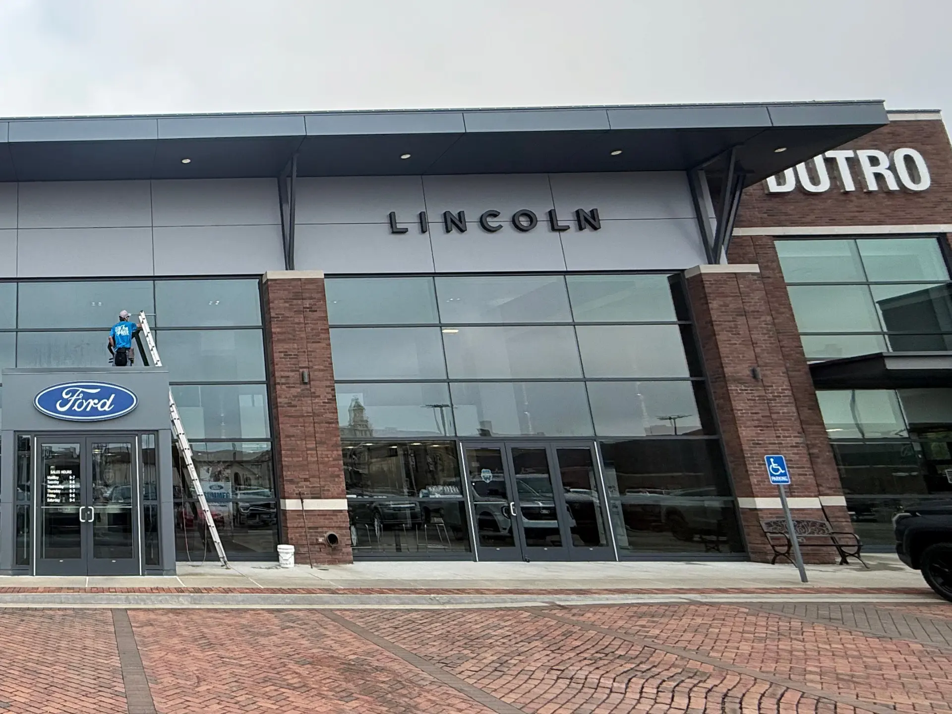 power clean technician using a ladder to reach high windows at Dutro Ford in Zanesville, OH