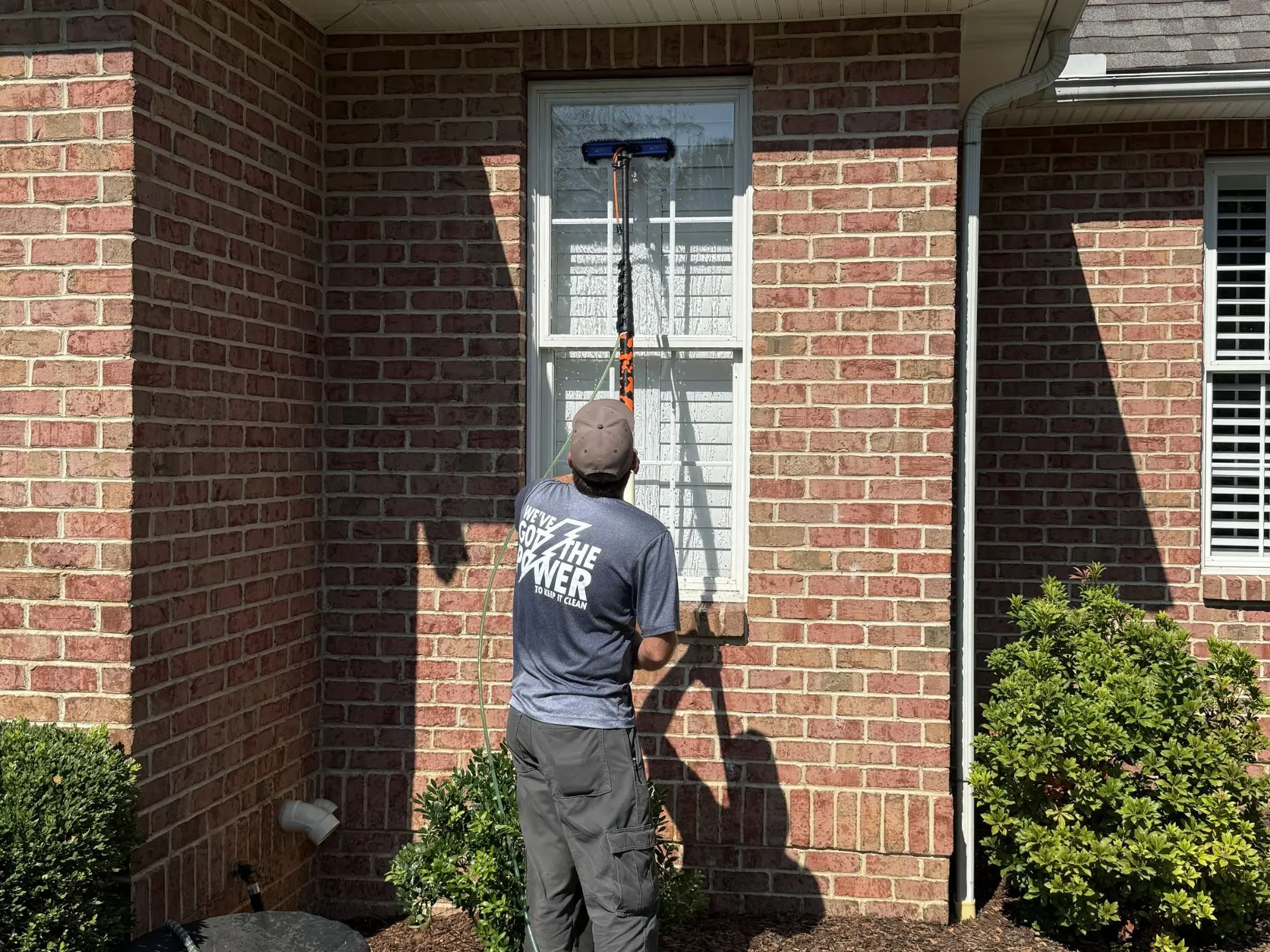 home-exterior-window-cleaning.webp close up of a power clean technician cleaniing the exterior windows of a house
