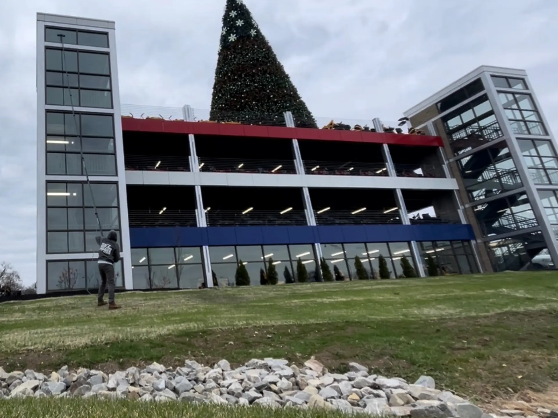Power clean technician using a waterfed pole to clean the exterior windows of a parking garage