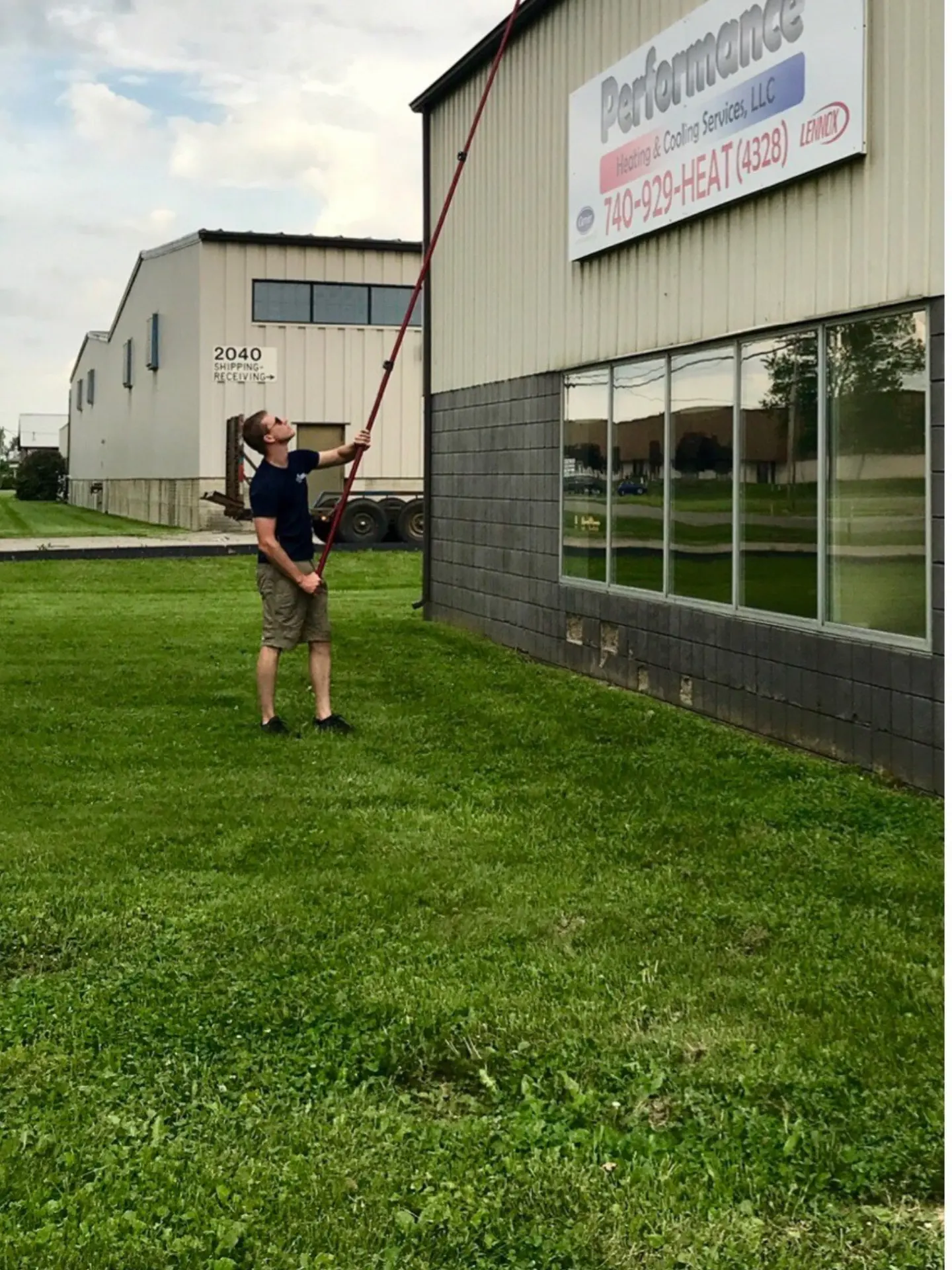 performance-heating-cooling-window-cleaning-heath power clean technician using a ladder to reach high windows at Dutro Ford in Zanesville, OH