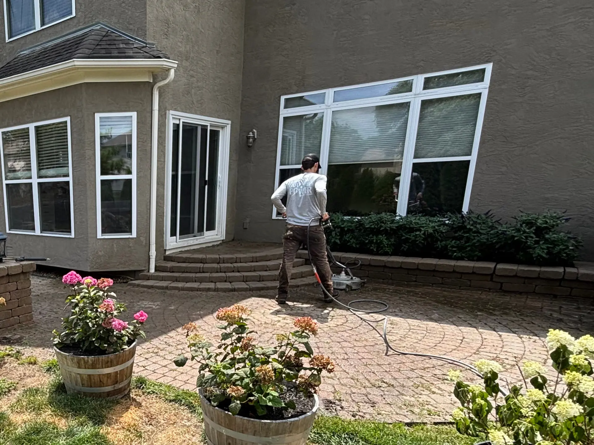 Power Clean technician pressure washing a brick back patio with a surface cleaner in Granville OH