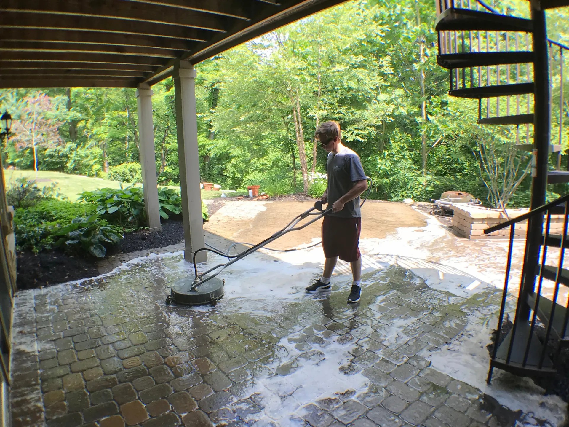 Power Clean technician using a surface cleaner to pressure wash a stone patio at a home in New Albany, OH
