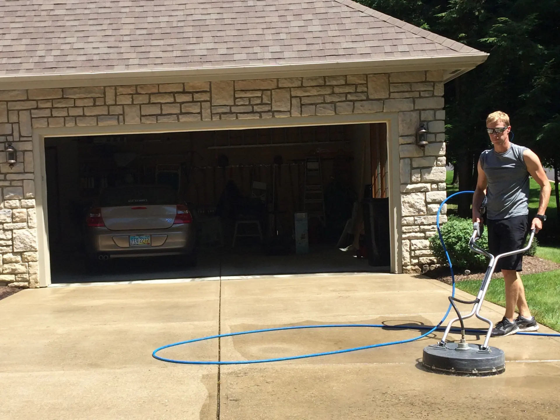 Power Clean technician pressure washing the concrete driveway with a surface cleaner in Zanesville OH