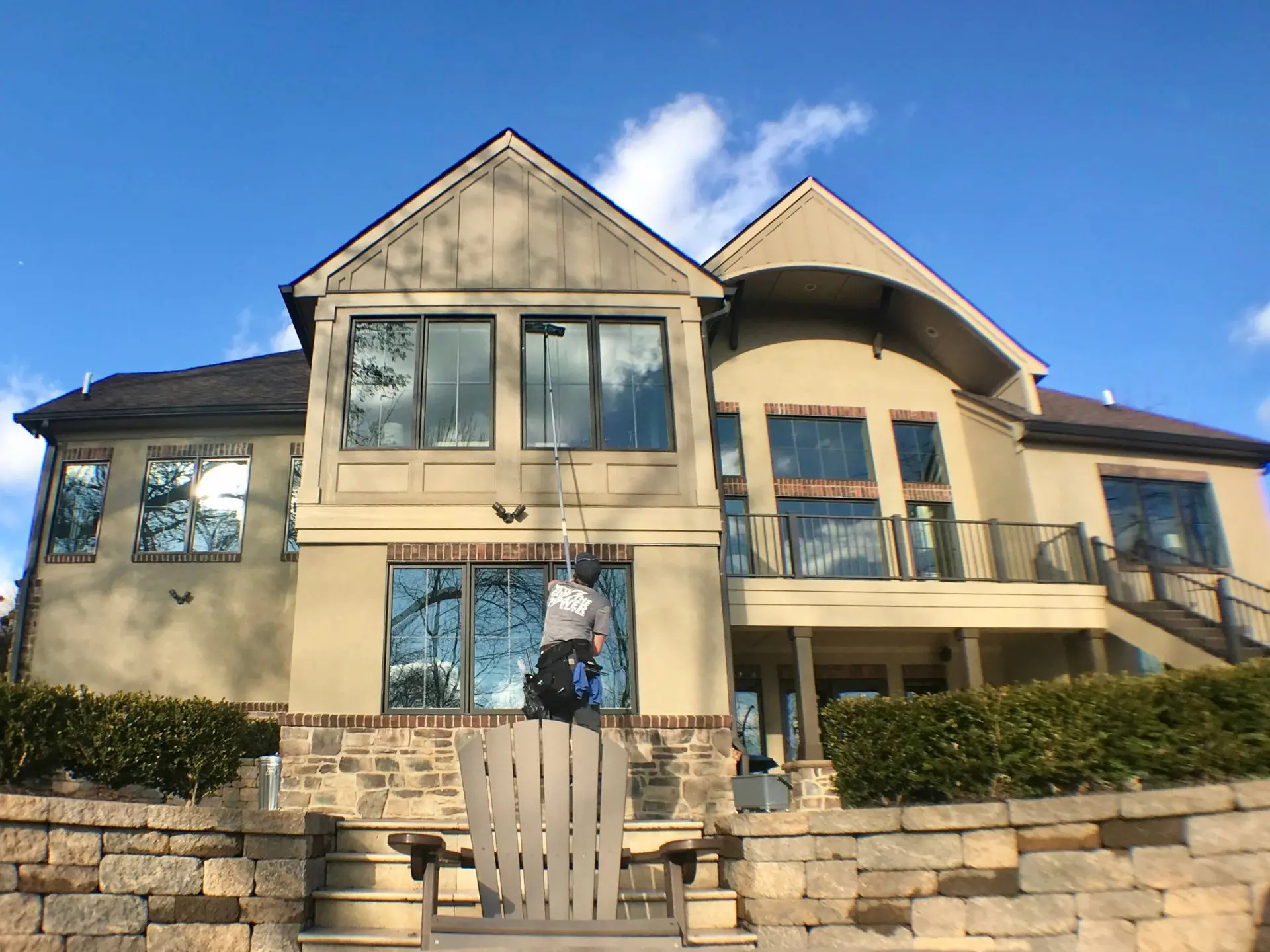 residential-exterior-window-cleaning.webp Power clean technician cleaning the second story exterior windows of a house